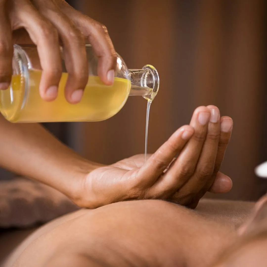 Manos de la esteticista con aceite para un tratamiento corporal