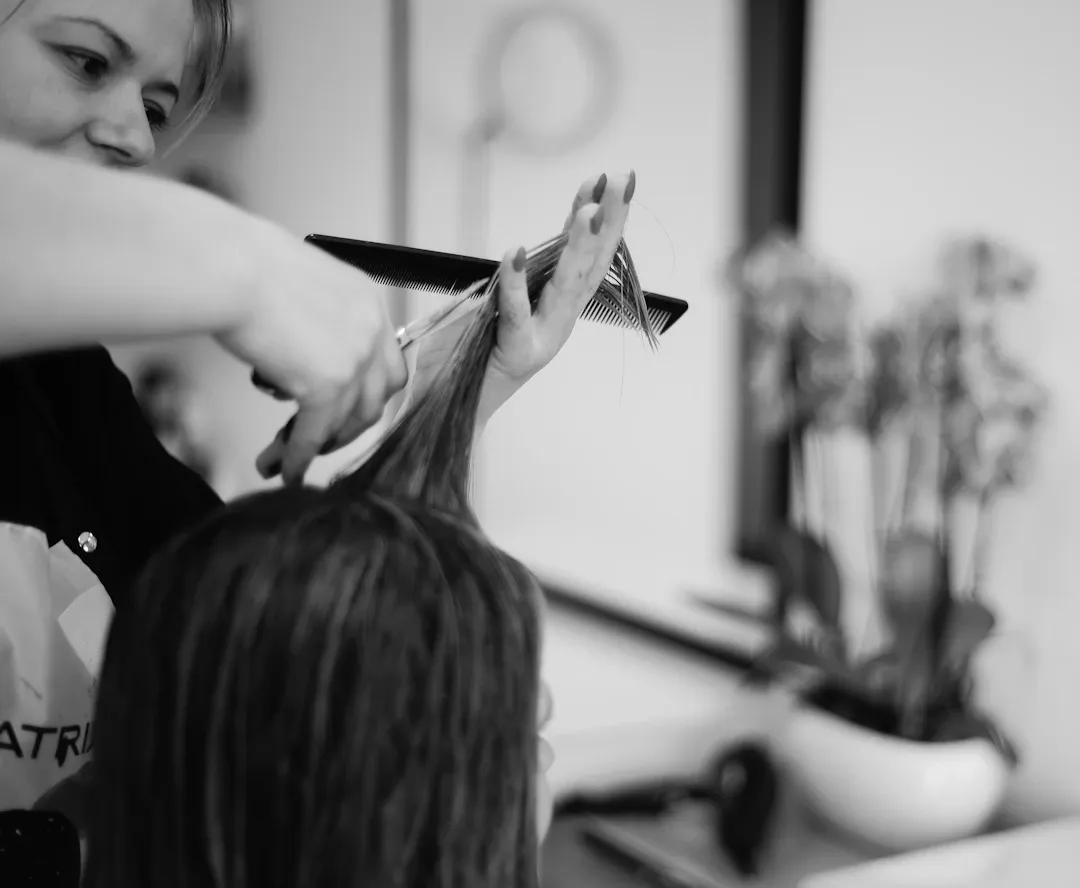 Peluquero cortando un mechón de pelo largo, en blanco y negro